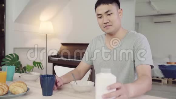 快乐的亚洲男人在早上醒来后吃早餐牛奶中的谷类食品面包和喝橙汁视频的预览图