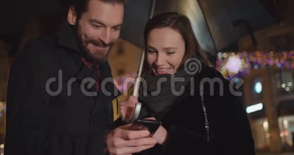 年轻的幸福夫妇晚上使用智能手机视频的预览图