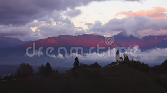 斯洛文尼亚贾姆尼克上空日落彩虹阿尔卑斯山和圣普雷莫兹教堂空中无人机景观视频的预览图