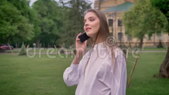 年轻漂亮的女孩夏天在公园打电话交流观念视频的预览图
