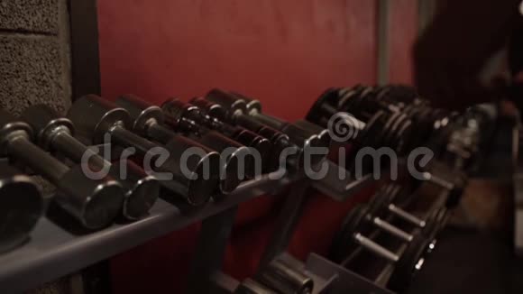 从健身房的储物架上拿哑铃的人视频的预览图
