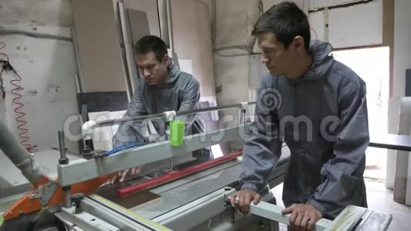 双胞胎工人在木工车间用桌子圆锯切割木材视频的预览图