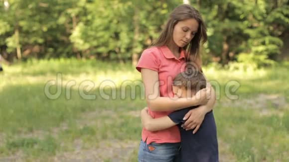 妈妈在公园里轻轻地拥抱她的儿子视频的预览图