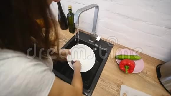 年轻漂亮的女人在现代厨房洗碗视频的预览图