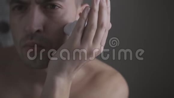 男人用泡沫和手动刮胡子把人的胡子修得很近视频的预览图