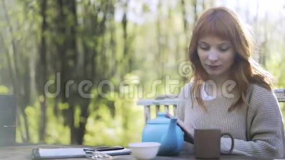 红头发的女人在公园里喝茶视频的预览图