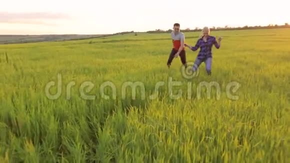 日落时分年轻的幸福夫妇在田野上奔跑视频的预览图