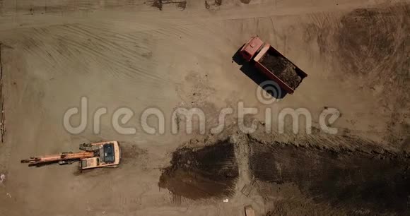 挖掘机的空中镜头将沙子倒入卡车视频的预览图