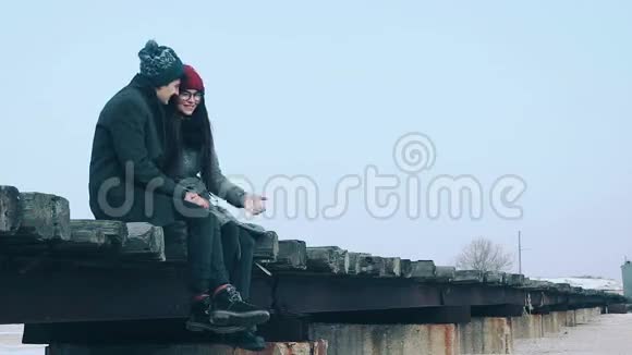 夫妻俩坐在桥上互相温暖手视频的预览图