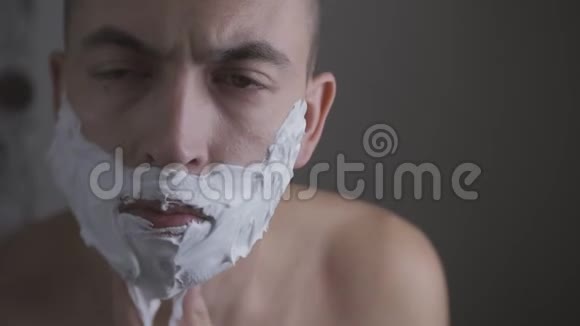 带泡沫和手动刮胡子的成年男子视频的预览图