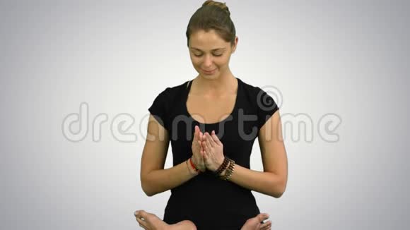 年轻女子坐在莲花瑜伽姿势中在白色背景下练习冥想视频的预览图