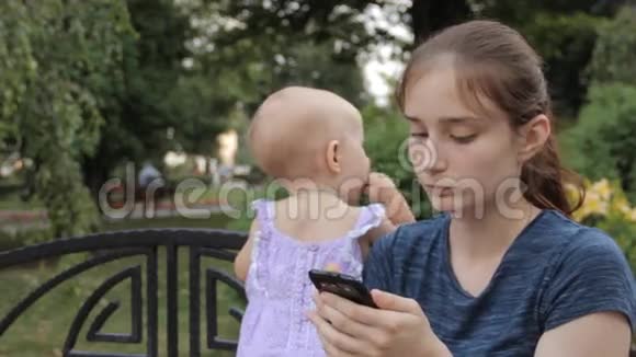 一个年轻的保姆跳进她的智能手机屏幕上的一张照片一手抱着一个女婴视频的预览图