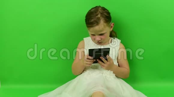 可爱的小女孩在色度键背景上阅读电子书穿着浪漫裙子的小女孩白色婚纱礼服视频的预览图
