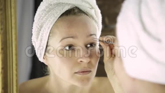 漂亮的女人拿着毛巾拨眉毛护肤和家庭水疗视频的预览图