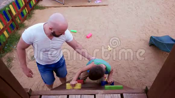 孩子爬上小山男孩爬到山顶父亲支持儿子一家人在公园的操场度假视频的预览图