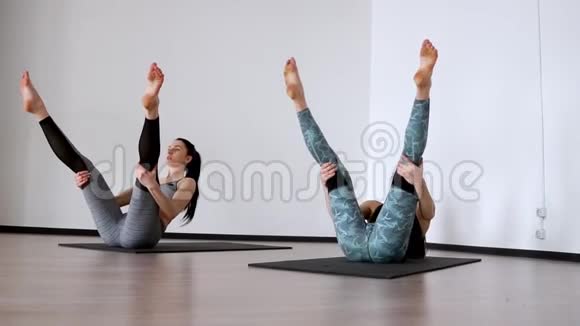 两个女孩在健身房里做一个运动彼拉多哈塞尔勒兹纳亚在她的背上她的腿抬起使她成为视频的预览图