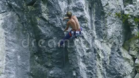 后景强壮的肌肉男攀岩者在户外运动路线上攀登垂直悬崖视频的预览图