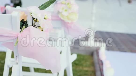 婚礼装饰在椅子上丝带和花在白色椅子上玫瑰和野花在婚礼的小花瓶里视频的预览图