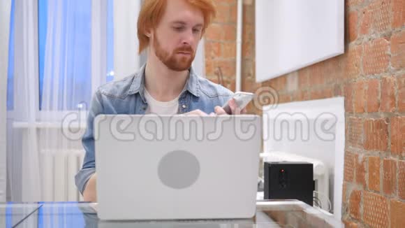红发胡子男子在线浏览智能手机打字视频的预览图