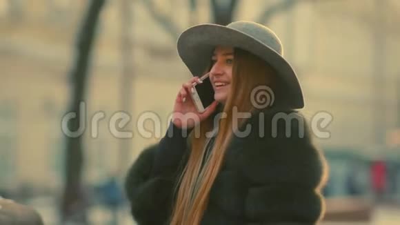 阳光明媚的年轻女子用手机微笑在电话中交谈视频的预览图