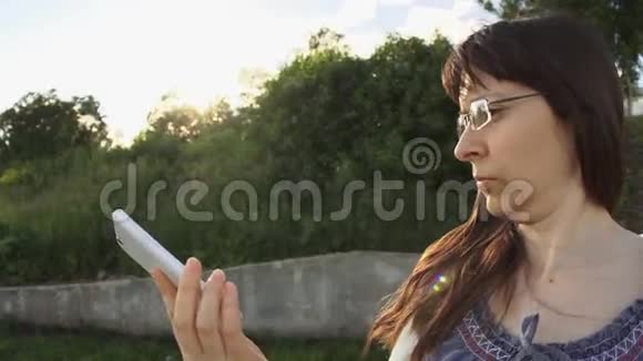 戴眼镜和一件白色针织夹克的年轻女子在打电话视频的预览图