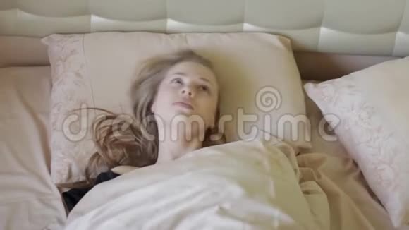 清晨躺在床上笑着的漂亮快乐的金发女孩视频的预览图