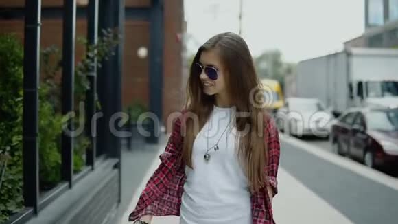 年轻貌美的女士戴着太阳镜穿着时髦的衣服在街咖附近散步查看时间视频的预览图