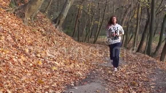 苗条的美国女运动员正在沿着秋天的公园慢跑女孩最后停了下来视频的预览图