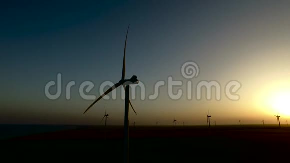 日落时大风力涡轮机在草原上的视野剪影航空测量视频的预览图