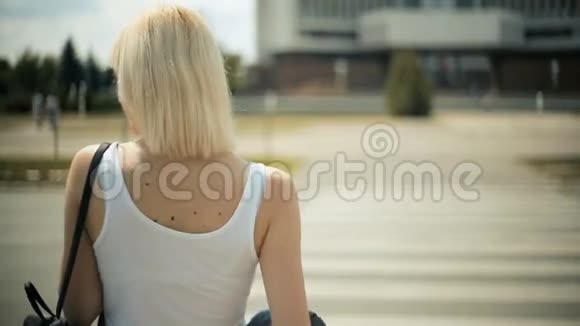 年轻的金发女郎等着车经过马路红灯过马路视频的预览图