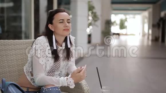 咖啡屋里的女孩坐在椅子上喝着杯子里的拿铁穿过一根稻草视频的预览图