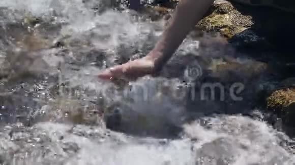 女孩在干净的山间小溪里打水视频的预览图