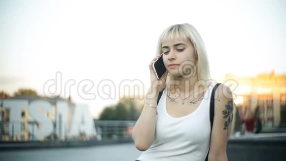 一位年轻的金发女子坐在电话里对着玻璃反射出的晚霞视频的预览图