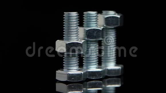 三个金属螺栓与螺丝螺母旋转黑色背景视频的预览图