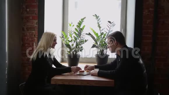 爱情夫妻坐在咖啡馆里吃甜点喝咖啡互相看着视频的预览图
