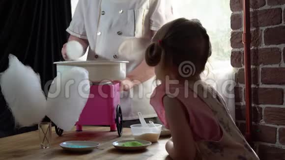 一个男厨师在一台特殊的机器上为一个可爱的小女孩做棉花糖视频的预览图
