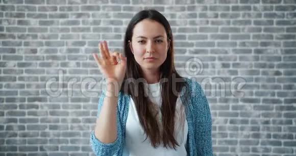 一幅欢快的女人画像展示了OK的手势微笑着看着相机视频的预览图