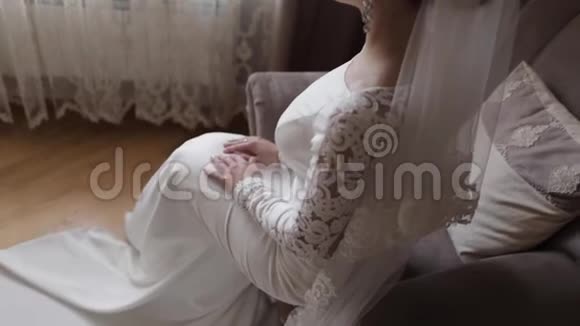 漂亮的新娘坐在家里的椅子上穿婚纱的美女视频的预览图