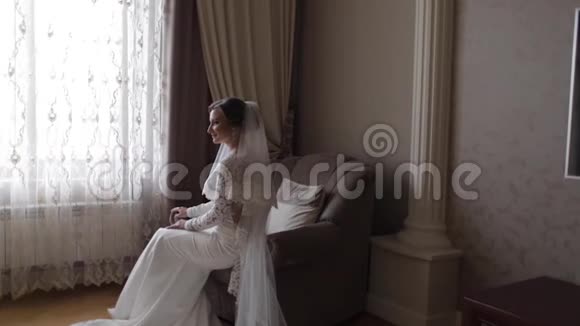 漂亮的新娘坐在家里的椅子上穿婚纱的美女视频的预览图