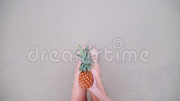 女子手持菠萝腿在海滩自拍的俯视图视频的预览图