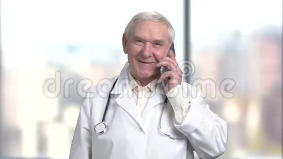 英俊的老年医生用听诊器在医院的手机上说话视频的预览图