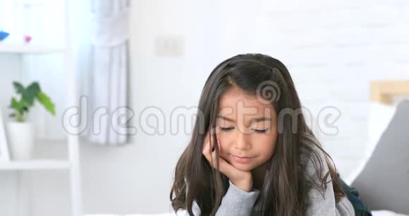 美丽的亚洲年轻的黑发女人在家里的床上看书脸上带着微笑视频的预览图