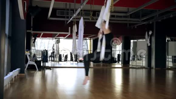 在宽敞的运动大厅里女人在空中吊床上摆动和跳跃视频的预览图