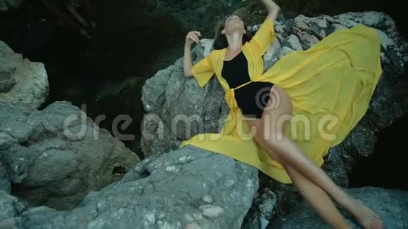 夏天迷人的女人躺在海边的岩石上视频的预览图