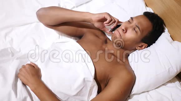 躺在床上用手机说话的非洲人视频的预览图