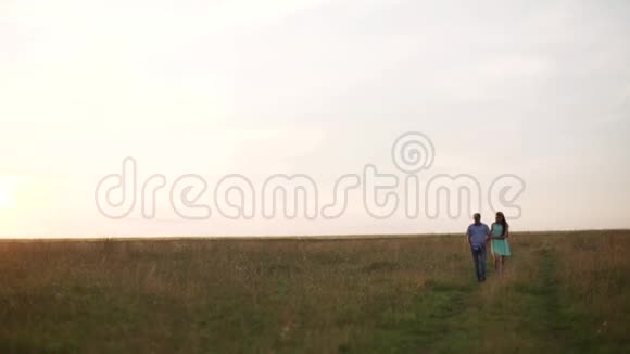一个男人和一个女孩拥抱沿着乡村的道路到田野日落夏天视频的预览图
