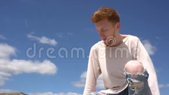 在蓝天的背景下一个年轻的红头发的高跷男子拍摄了Stadicam视频的预览图