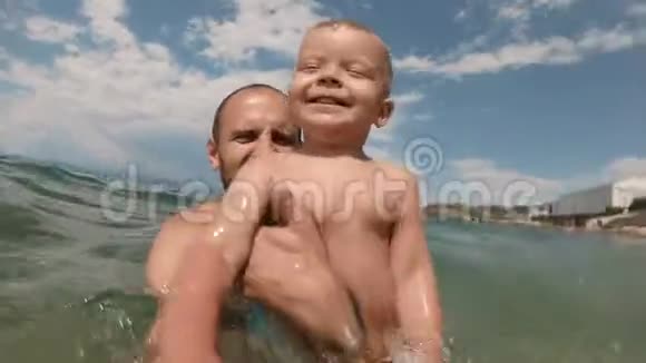 快乐的父亲和儿子一起在海滩上自拍视频的预览图