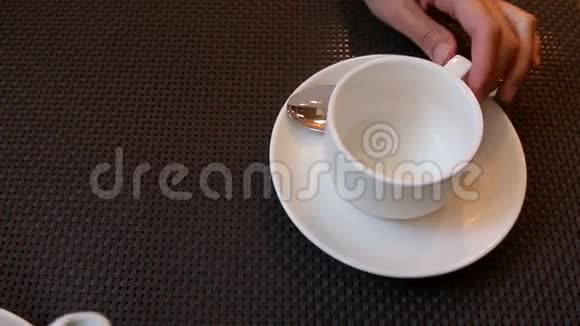 女孩用白色的小杯子从一个小白瓷茶壶里倒茶视频的预览图
