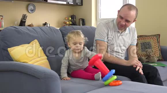 可爱的小女孩和爸爸在房间的沙发上嬉戏4K视频的预览图